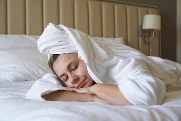 Gelukkige vrouw die op het bed ligt na het douchen thuis of in een hotelkamer