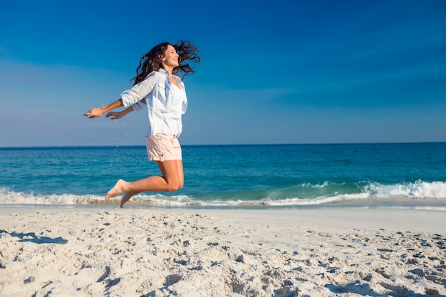 Gelukkige vrouw die op het strand springt