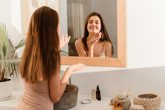 Gelukkige vrouw die 's ochtends dagelijkse routine doet om de huid te hydrateren