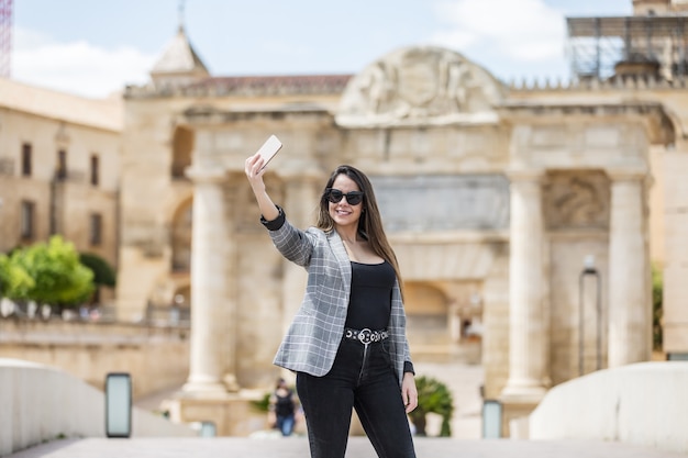 Gelukkige vrouw die selfie neemt tegen historisch gebouw