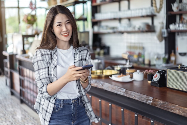 Gelukkige vrouw die smartphone in koffie gebruiken