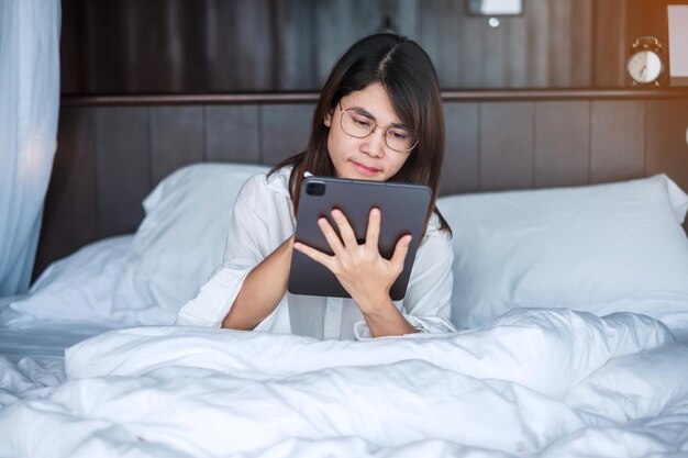 Gelukkige vrouw die tablet gebruikt voor sociale media jonge vrouwen kijken naar films op computerpad op bed thuis technologienetwerk online winkelen e-commerce levensstijl en digitaal communicatieconcept