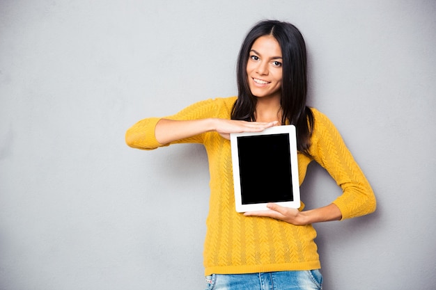 Gelukkige vrouw die tabletcomputer toont