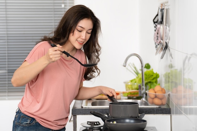 Foto gelukkige vrouw die thuis in de keuken kookt en voedsel bereidt