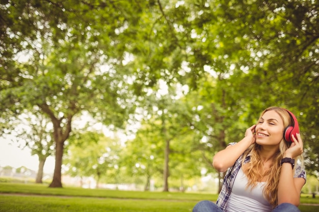 Foto gelukkige vrouw die van muziek met ogen geniet die bij park worden gesloten