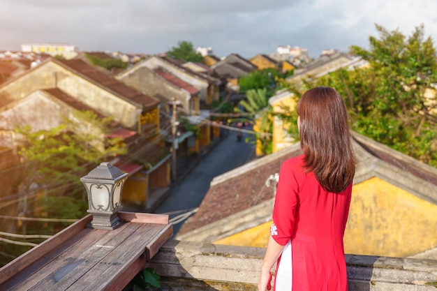 Gelukkige vrouw draagt Ao Dai Vietnamese jurk reiziger bezienswaardigheden bekijken op het dak van Hoi An oude stad in Vietnam oriëntatiepunt en populair voor toeristische attracties Vietnam en Zuidoost-reisconcept