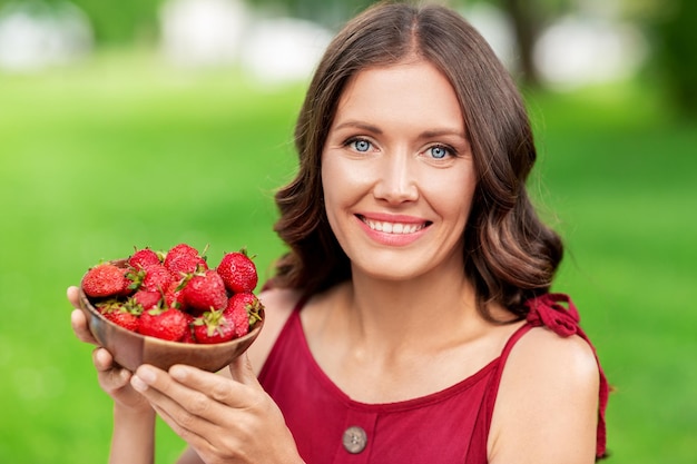 Gelukkige vrouw eet aardbeien in het zomerpark.