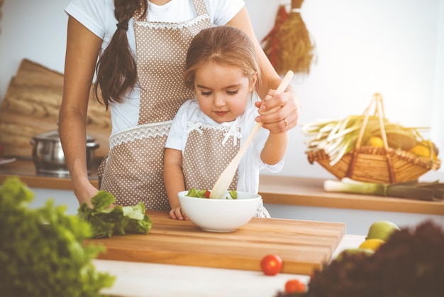 Gelukkige vrouw en haar dochter zijn op zoek naar nieuwe recepten voor een familiefeest in de zonnige keuken