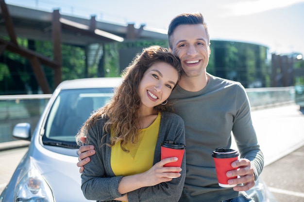 Gelukkige vrouw en man die haar koesteren die zich met koffie bevinden