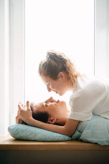 Gelukkige vrouw en man knuffelen in de buurt van venster in huis