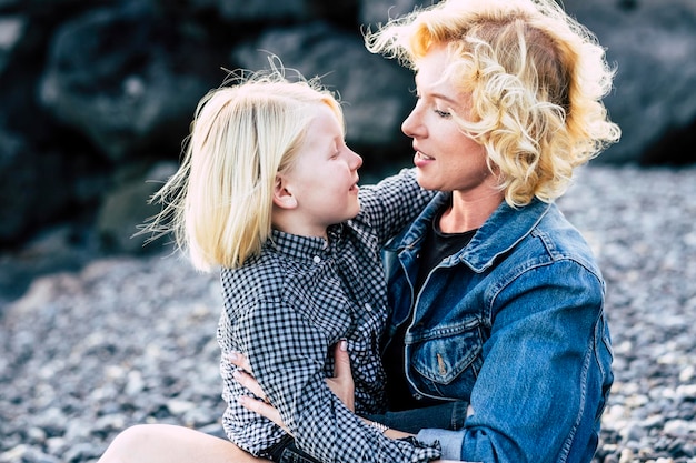 Foto gelukkige vrouw en zoon met blond haar zitten op het strand.