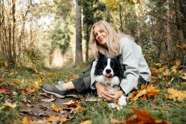 Gelukkige vrouw en zwart-witte border collie-hond in de herfstbos