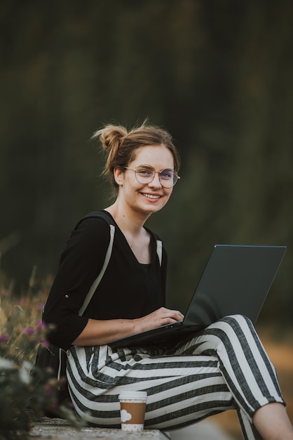 Gelukkige vrouw freelancer met bril die op laptop werkt