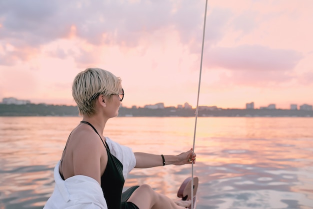 gelukkige vrouw genieten van zonsondergang op het jacht in de zee
