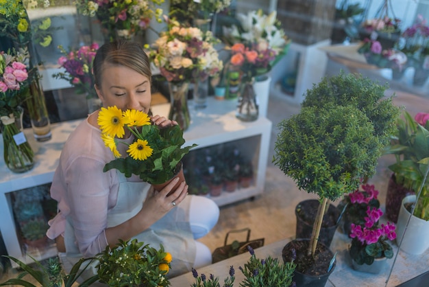 gelukkige vrouw het verzorgen van bloemen in bloemenwinkel