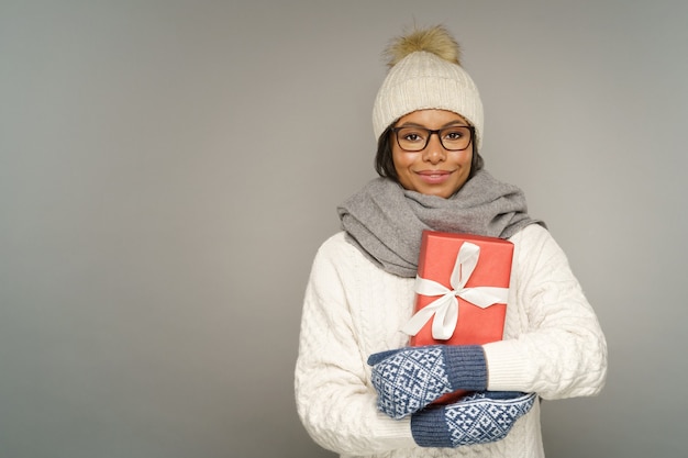 Gelukkige vrouw houdt kerstcadeau vrolijke vrouw in warme winterkleren muts en wanten knuffel de huidige doos