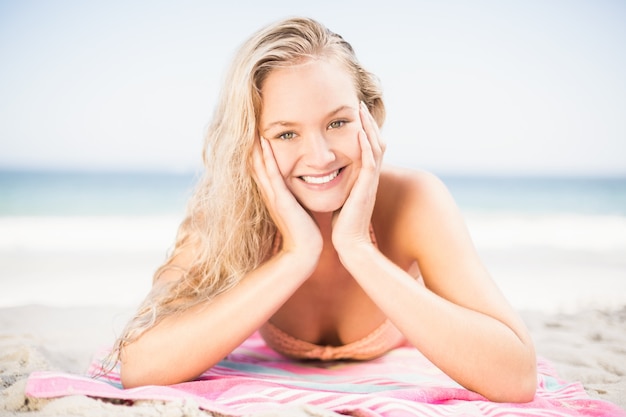 Gelukkige vrouw in bikini die op het strand ligt