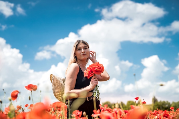 Gelukkige vrouw in casual doek op gebied van papavers genieten van vrije zomertijd