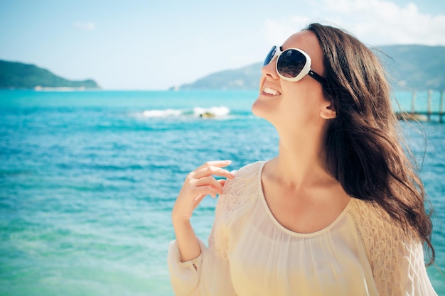 Gelukkige vrouw in de zomer witte jurk op het strand. Kaukasisch meisje ontspannen en genieten van rust op vakantie.