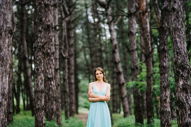 Gelukkige vrouw in een turquoise lange jurk in een groen park