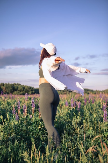 Gelukkige vrouw in het midden van het veld met Lupinus-bloemen kopiëren ruimte