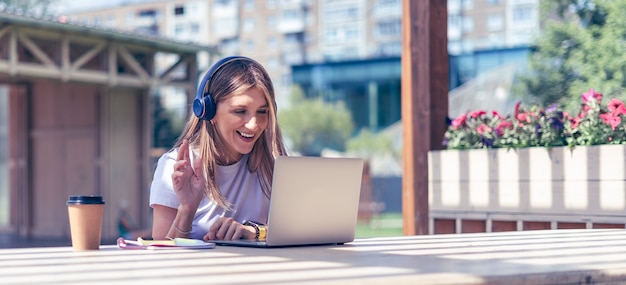 Gelukkige vrouw in hoofdtelefoons die een videogesprek op haar laptop hebben