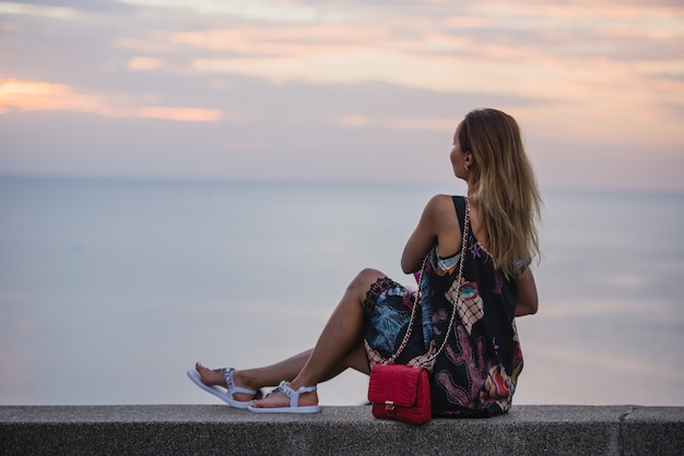 Gelukkige vrouw in korte jurk kijken naar de zee