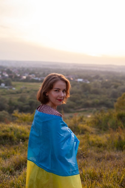 Gelukkige vrouw in lange jurk met een gele en blauwe vlag van Oekraïne