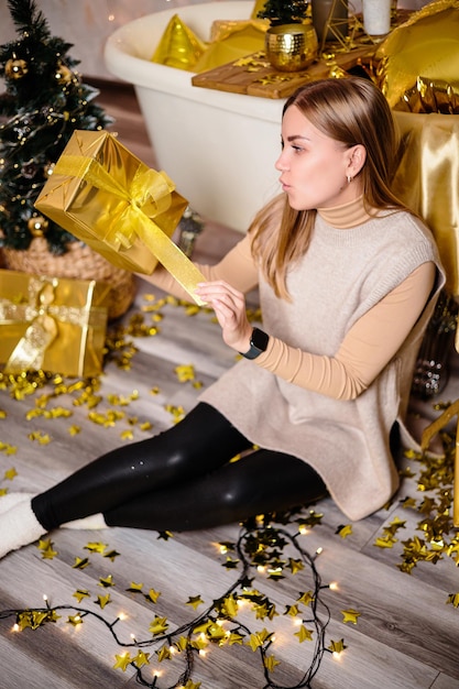 Gelukkige vrouw in nieuwjaarskamer Nieuwjaarsdecoratie van de kamer in gouden kleur Het concept van de vakantie en het feestelijke ontwerp Woondecoratie voor het nieuwe jaar
