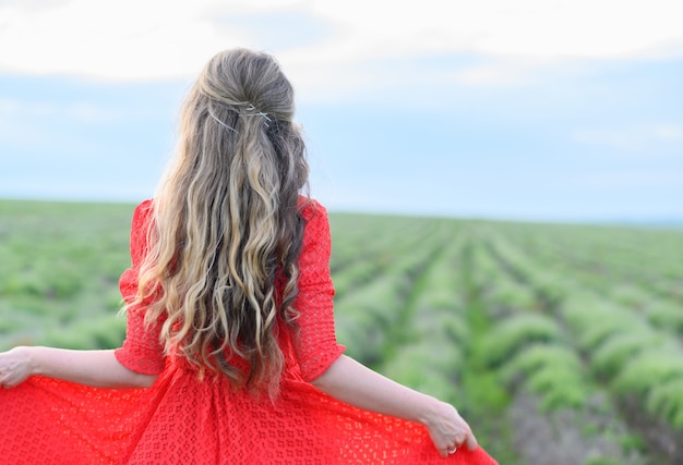 Gelukkige vrouw in rode jurk dansen en springen in lavendel veld