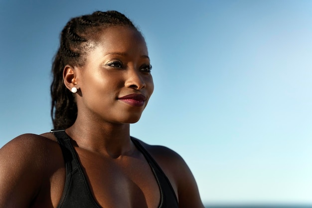 Gelukkige vrouw in sportoutfit die wegkijkt en glimlacht