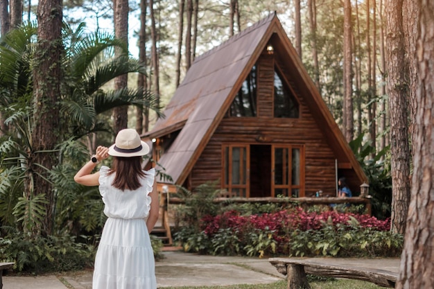 Gelukkige vrouw in witte jurk en hoed reizen in dennenbos, toeristisch bezoek aan doi bo luang, chiang mai, thailand, landmark en populair voor toeristische attracties. vakantie- en reisconcept