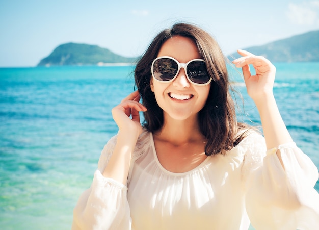 Gelukkige vrouw in witte zomerjurk op strand