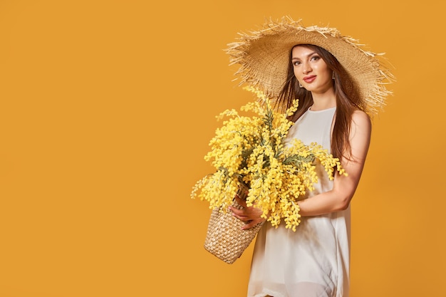 Gelukkige vrouw in zomer witte jurk stro hoed met bos bloemen in tas