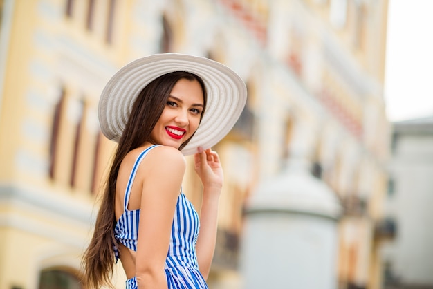 Gelukkige vrouw in zomerjurk poseren met strooien hoed