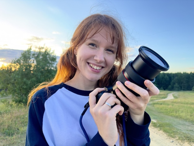 Gelukkige vrouw is een professionele fotograaf met een dslr-camera buiten en zonlichtportret