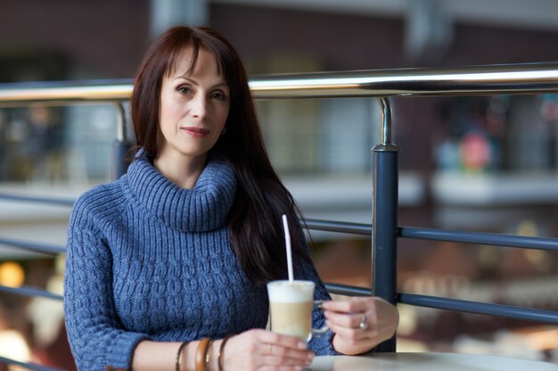 Gelukkige vrouw koffie drinken in café