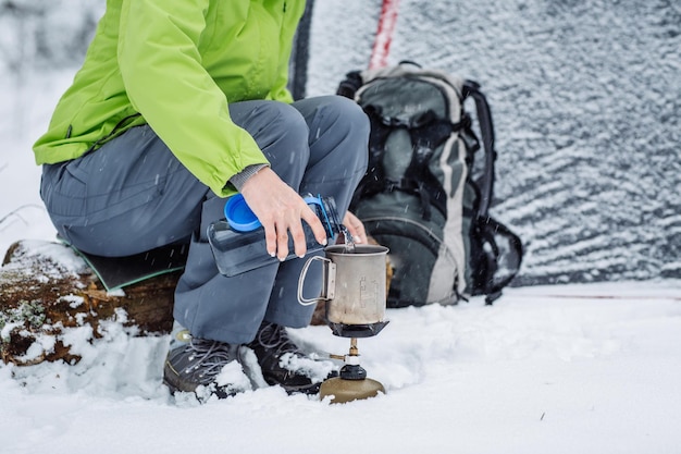 Gelukkige vrouw koken in de buurt van wintertentenkamp in het sneeuwbos