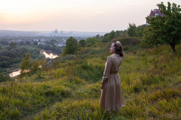 Gelukkige vrouw loopt bij zonsondergang op een heuvel met uitzicht op de rivier