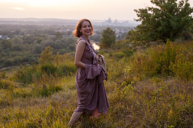 Gelukkige vrouw loopt bij zonsondergang op een heuvel met uitzicht op de rivier