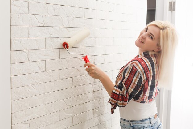 gelukkige vrouw maakt reparaties in de kamer thuis