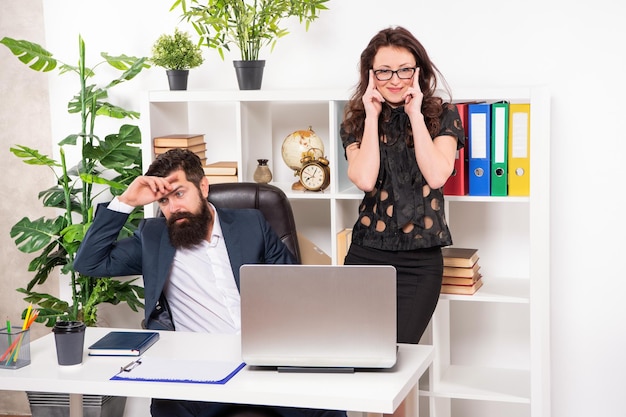 Gelukkige vrouw manager lacht naar man moe van het werken in kantoorwerk