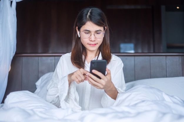 Gelukkige vrouw met behulp van slimme telefoon voor video-oproep, vrouwelijke vergadering online via mobiele telefoon op bed. technologie, netwerk, thuiswerken, lifestyle en digitaal communicatieconcept