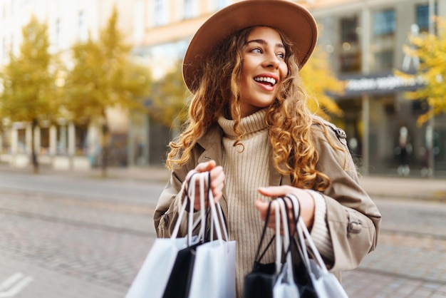 Gelukkige vrouw met boodschappenzakken die op straat loopt Koop zwarte vrijdag kortingen verkoopconcept