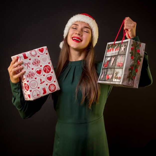 Gelukkige vrouw met doos en cadeauverpakking op zwarte achtergrond Kerstcadeaus