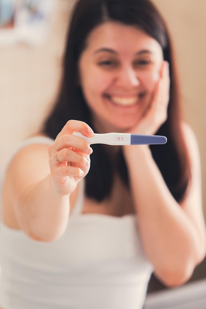 Gelukkige vrouw met een positieve zwangerschapstest van dichtbij.