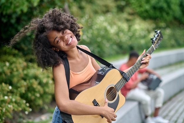 Gelukkige vrouw met gitaar en man achter in park