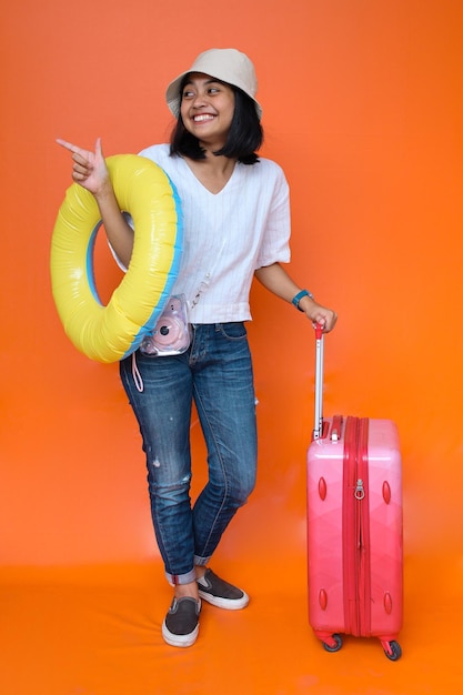 Gelukkige vrouw met koffer die op zomervakantie gaat. glimlachend dolblij jong meisje dat een vrijetijdskleding draagt