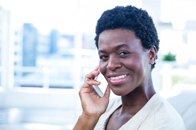 Gelukkige vrouw met mobiele telefoon thuis