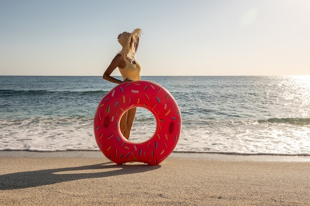 Gelukkige vrouw met opblaasbare doughnut op een tropisch strand